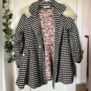 Black and white houndstooth coat with faux fur collar and belt.
